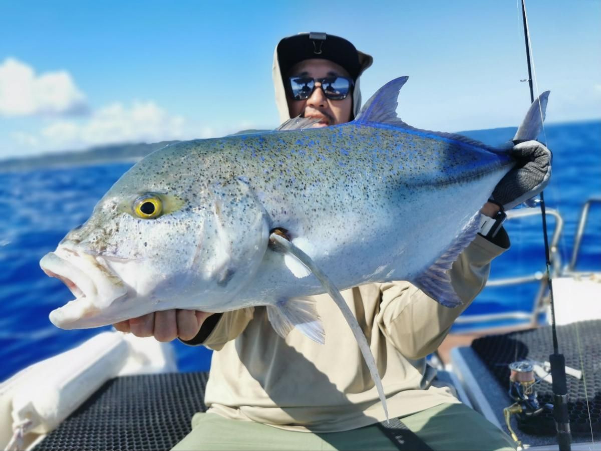 Angler holding a bluefin trevally with bright blue spots