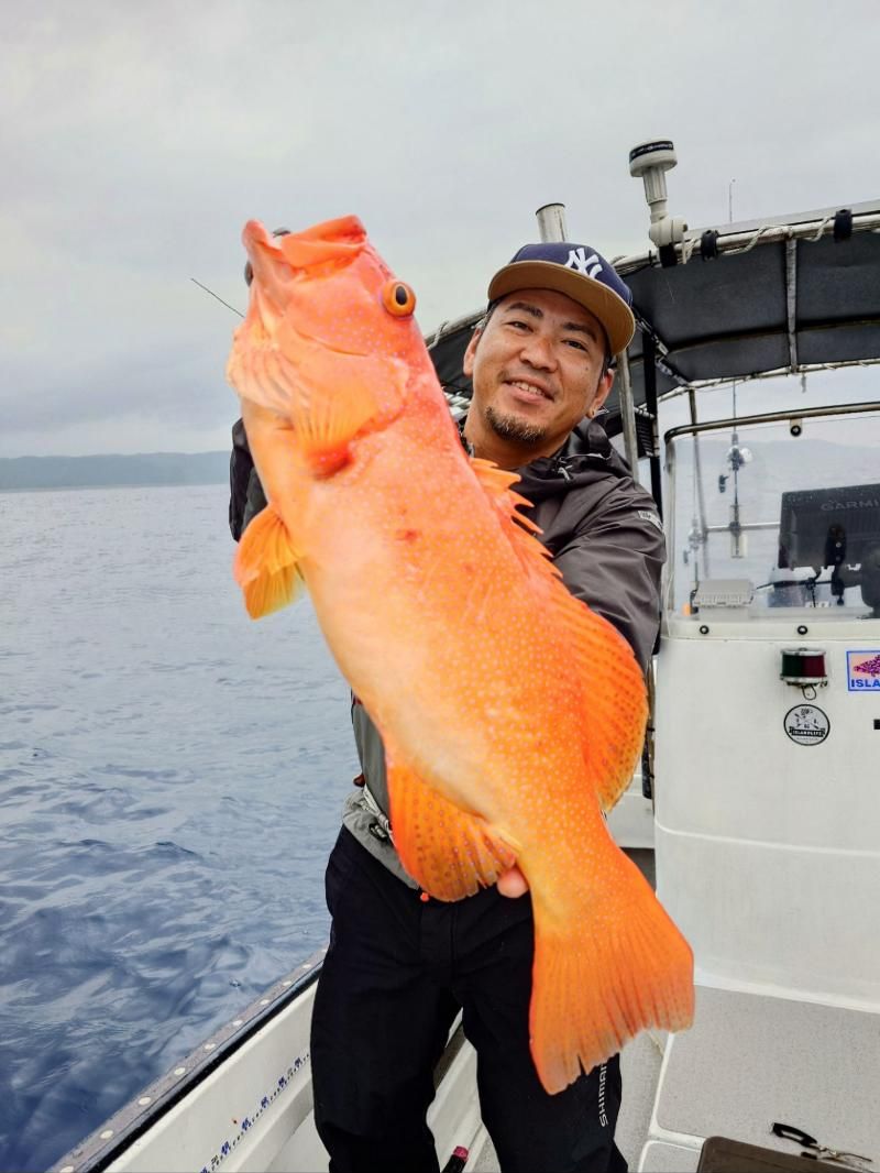 Smiling angler holding an orange spotted coral grouper