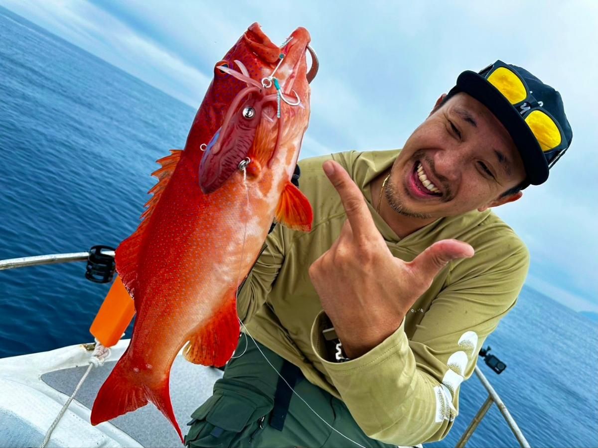 Red coral trout held up with a jig in its mouth