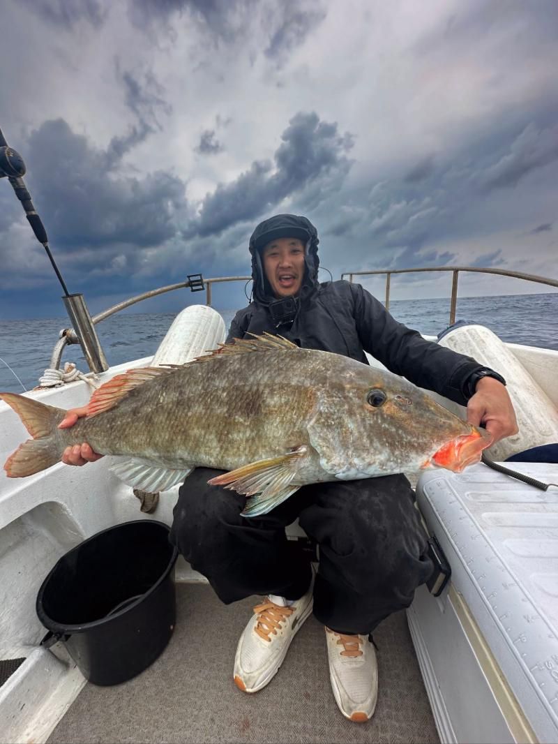 Angler under storm clouds holding a large reef fish